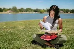 woman looking at documents while sitting on grass