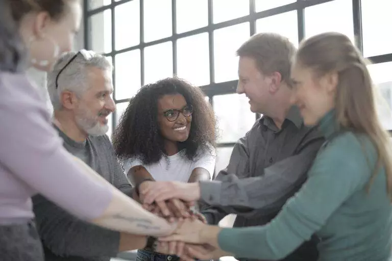 happy multiracial coworkers uniting hands after making decision