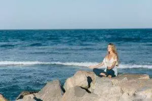 woman meditating near sea