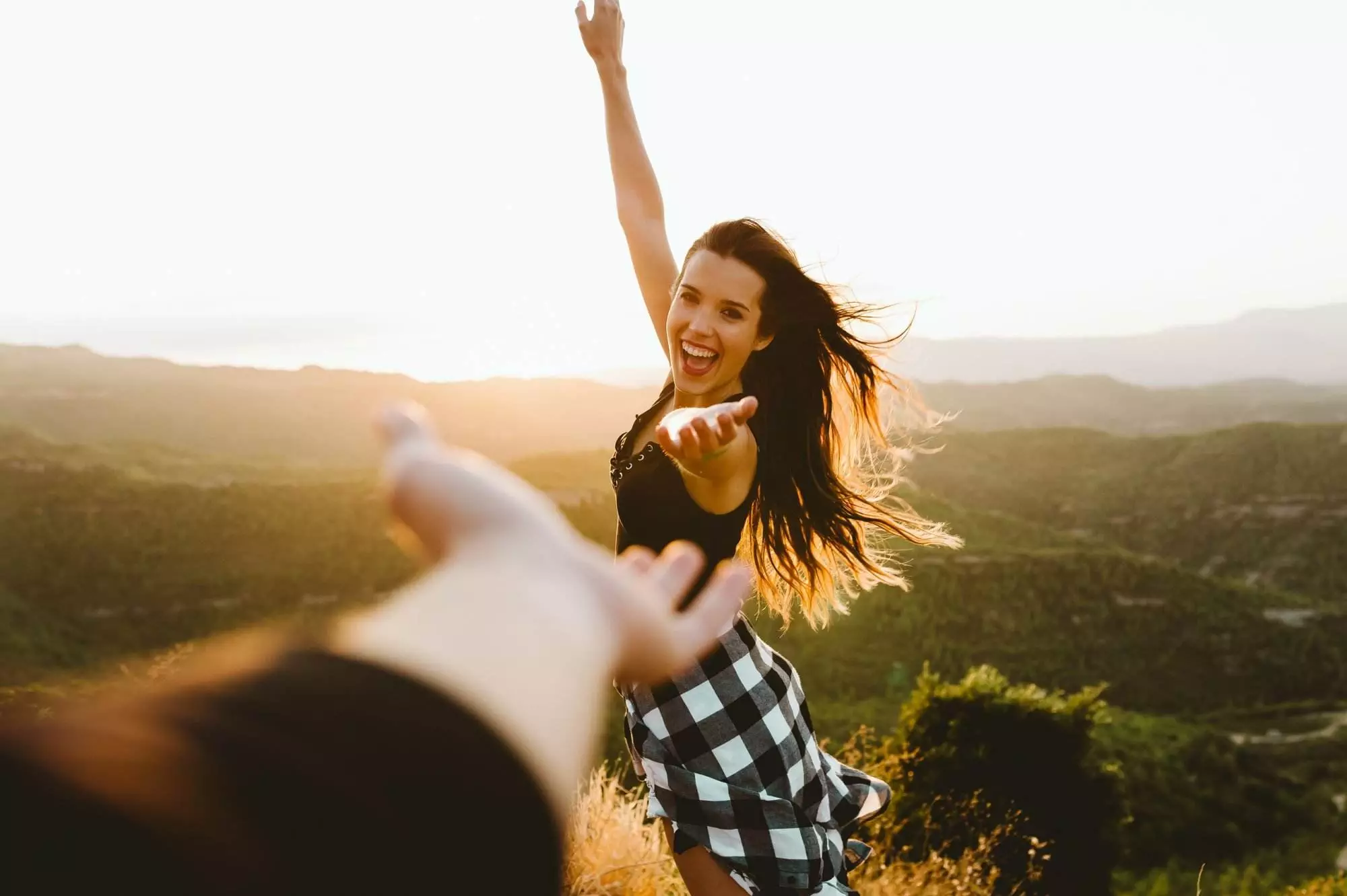 Happy woman with arm stretched toward blurred arm outdoors