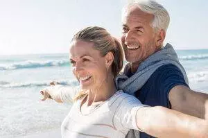 Smiling mature man and woman with arms out from shoulders