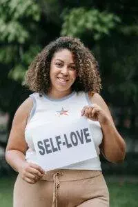 woman holding paper with self love written on it